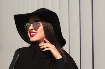 Happy young model in mirror glasses and broad brimmed hat posing near the shutters