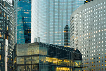 Modern buildings in Paris business district La Defense. Night cityscape with glass facades of skyscrapers. City lights, urban architecture, contemporary city life. Economy, financial activity concept