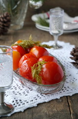 Pickled tomatoes with carrot tops in a glass dish