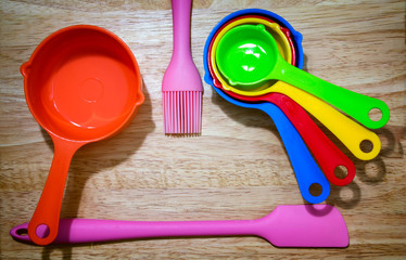 Set of Colorful Measuring Spoon, pink Spatula and Brush on a Wooden Background