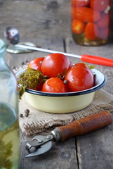Pickled tomatoes with pepper and carrot tops in a bowl