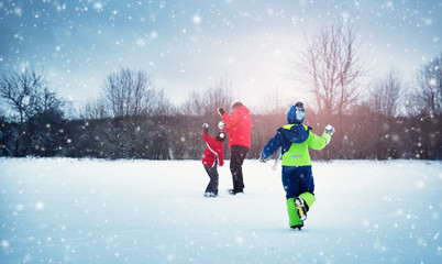 Father with sons walking at snowfall. Children in winter clothes playing with snow and sledding...