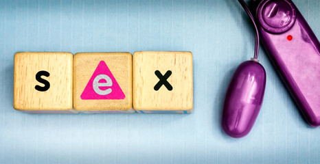 Wooden Dice Spells SEX next to a Purple Vibrator .