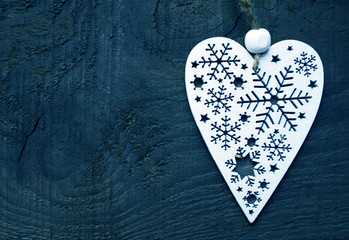 Christmas decoration.Decorative white christmas heart on dark blue wooden background.Selective focus.