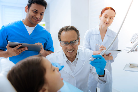 Education process. Nice positive smart interns looking at their mentor and taking notes while wanting to get experience