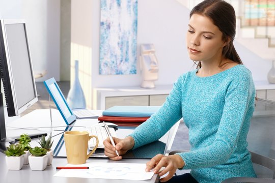 Casual young woman working home desk pen in hand
