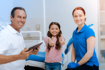 Fototapeta premium Everything is great. Happy positive cute girl sitting together with her mother and smiling while showing OK gesture