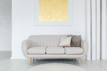 Gold painting above grey sofa