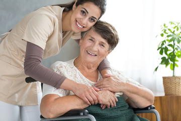 Pretty caregiver hugging disabled senior