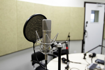 Professional condenser studio microphone over the musician blurred background and audio mixer, Musical instrument Concept.