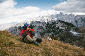 Fototapeta premium Mountain and nature photographer with his backpack and equipment on the mountain peak taking a photograph