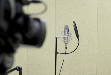 Professional condenser studio microphone over the musician blurred background and audio mixer,...
