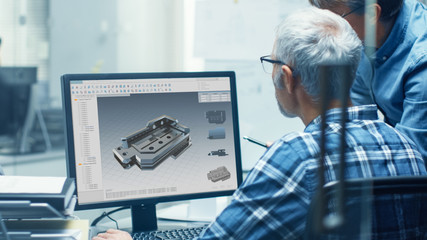Two Senior Engineers Working With Detail Blueprint on a Personal Computer. They Actively Discuss...