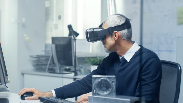 Virtual Reality Engineer Works with VR Glasses On while Simultaneously Doing Programming on His Personal Computer.