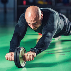 Man exercising abs on roller in the gym