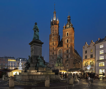 Adam Mickiewicz Monument opposite the St. Mary's Basilica and Christmas market on the Main Square of Krakow in twilights, Poland. The monument was erected in 1898.