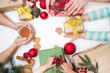 People are packed and wrapped packing Christmas gifts. Top view. Christmas family traditions.