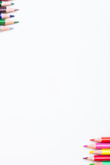 Colored pencils on a light background. White box for your text with pencils. Vertical photo