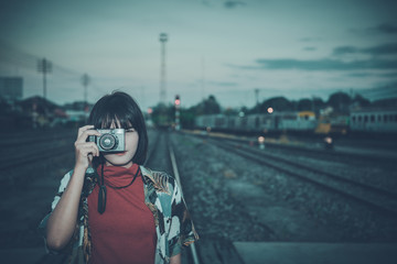 Portrait of asian hipster girl on sunset at railway vintage style,Grain and noise has been added to make effect of photographic film.