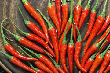 Natural food background with red chili peppers pods close up. Flat lay on brown earthenware surface.