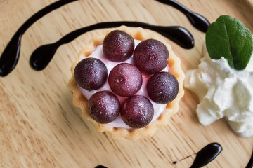 Selective focus tart grapes cream cheese on the wood desk in coffee shop.
