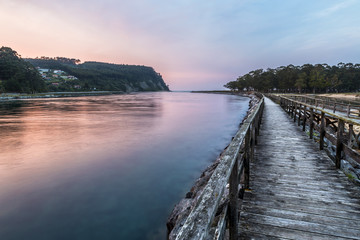 Obraz premium Puesta de sol sobre un río y un paseo de madera