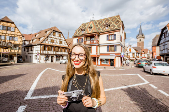 Portrait of a young woman tourist with photo camera standing on the old square in Obernai village in Alsace in north-eastern France