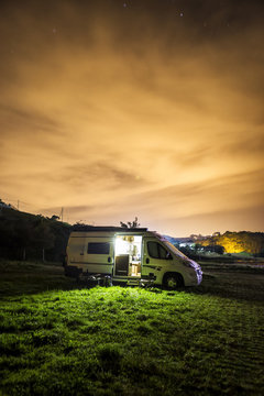 Fotografía nocturna de una autocaravana aparcada sobre un prado
