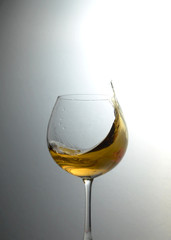 Whiskey splashing motion in a glass with lighting background vignette. A drink action in a glass
