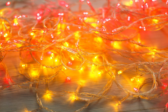 Christmas red and yellow lights border on light wooden background