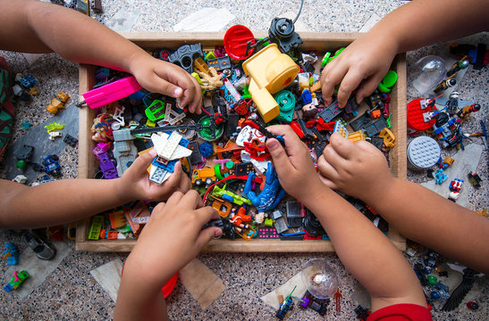 The hands of many children who are playing toys together.