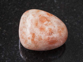 polished sunstone (heliolite) gem stone on dark