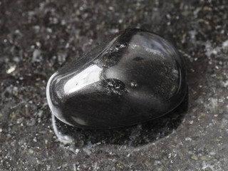 polished black obsidian gem stone on dark