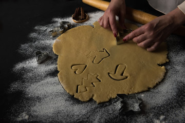 process of cooking home cookies, gingerbread. Hands carving figurine cookie figures. dark photo, home atmosphere of the holiday, preparation for Christmas, new year.
