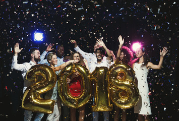 Group of young happy friends with number balloons at new year party