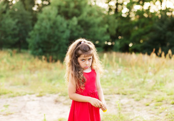 Portrait of cute sad little girl looking worried  at summer day
