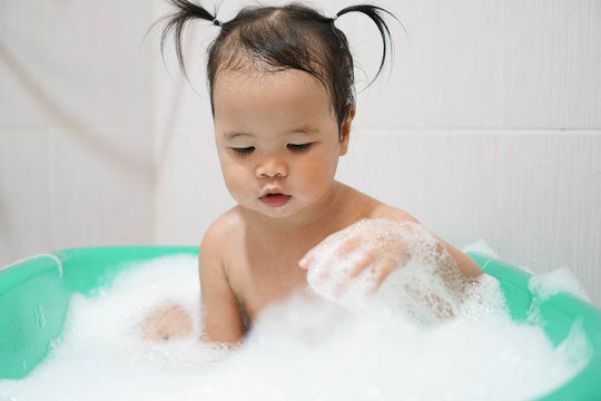 Little asian girl taking bath foam bubbles in bathtub, Toddler 1.8 years old taking bath by herself