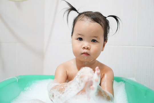 Little asian girl taking bath foam bubbles in bathtub, Toddler 1.8 years old taking bath by herself