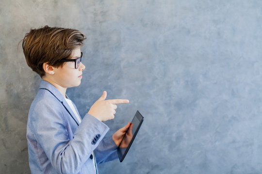 Teen schooler boy in eyeglasses holds tablet PC