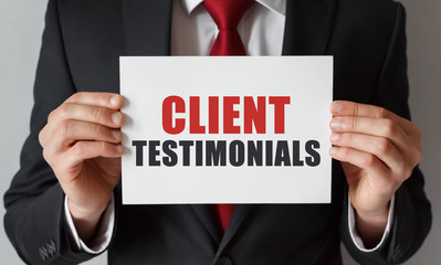 Businessman holding a card with text Client Testimonials