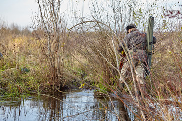 Hunter in camouflage clothes with hunting rifle during a winter hunting