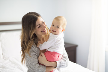 Mother and baby child on a white bed.