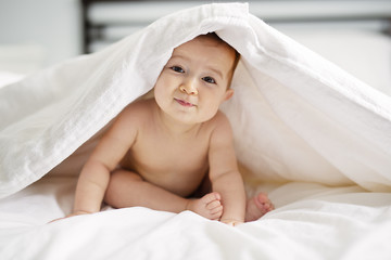 baby girl sit on white sheet