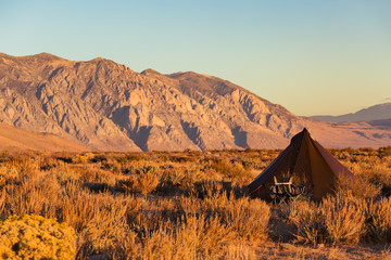 Indian style tipi tent with folding camp chair nearby pitched in the desert under the mountains of the Sierra Nevada © Jeremy Francis