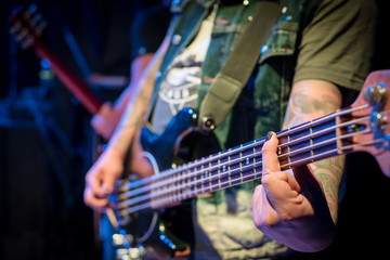 Naklejka premium Bass guitarist clamps the chord with his finger on the guitar during the concert