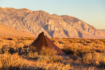 Indian style tipi tent with folding camp chair nearby pitched in the desert under the mountains of the Sierra Nevada © Jeremy Francis