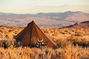 Indian style tipi tent with folding camp chair nearby pitched in the desert under the mountains of the Sierra Nevada © Jeremy Francis