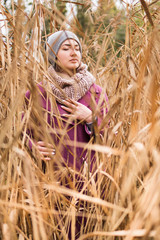 Portrait of a beautiful woman in a coat with closed eyes among bulrushes