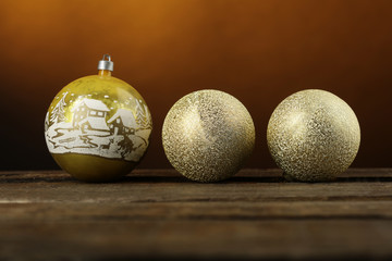 3 Palle di natale decorative color oro e con fantasia natalizia sopra superficie in legno  su sfondo arancio