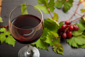 Red wine glass and fresh grapes on black background